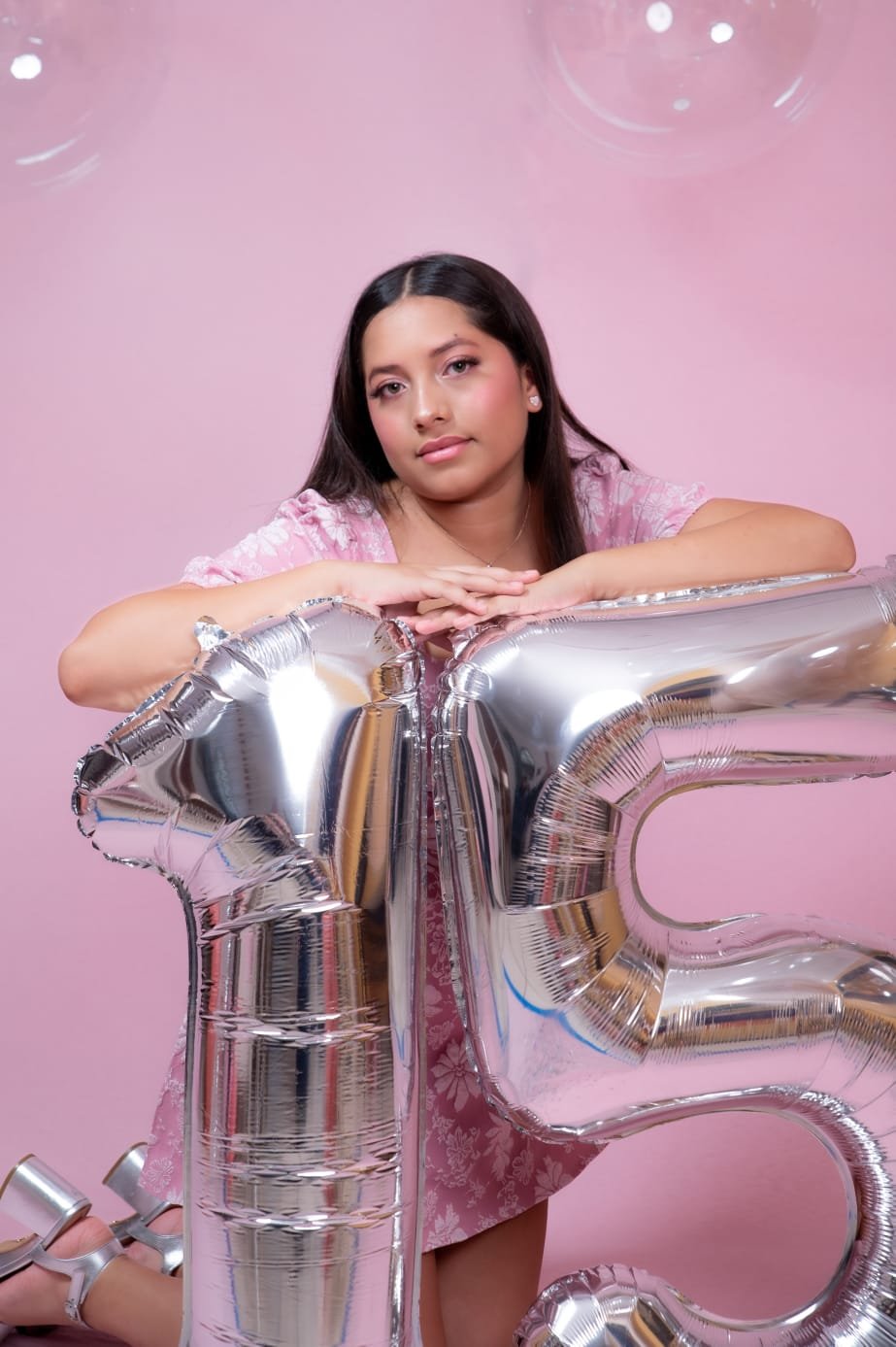 Talía apoyada en globos plateados